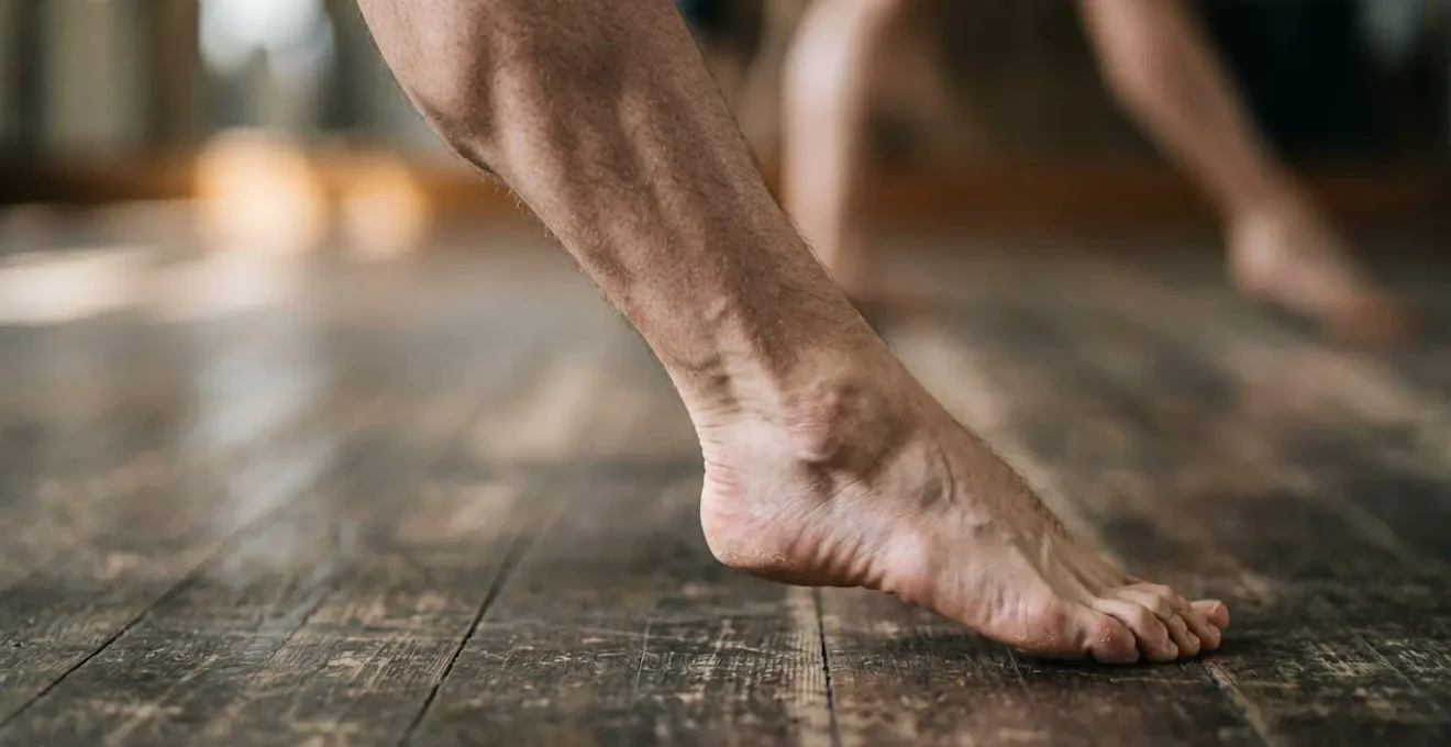 Close-up of a dancer's lower leg and foot making contact with the ground during landing, showing muscle engagement and joint alignment