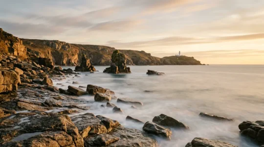 A dramatic Cornish coastal scene with silky water flowing over rocks at golden hour