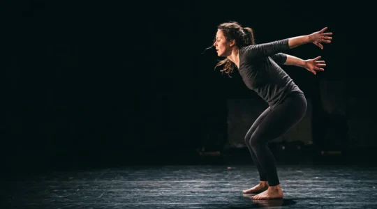 A physical theatre performer in mid-movement conveying intense emotion through body language alone